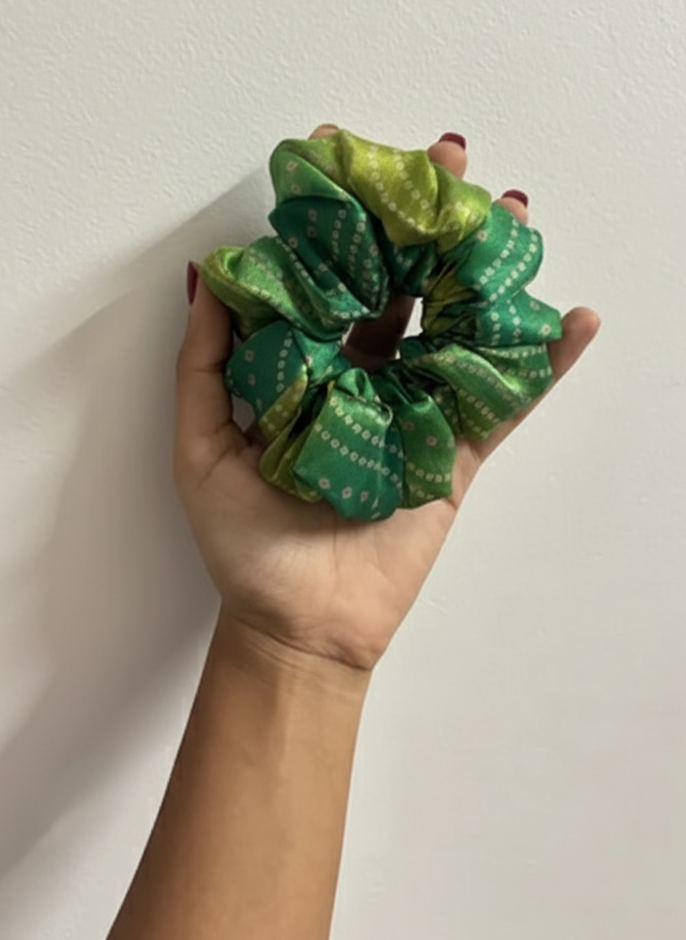 Hand holding a green scrunchie against a white background
