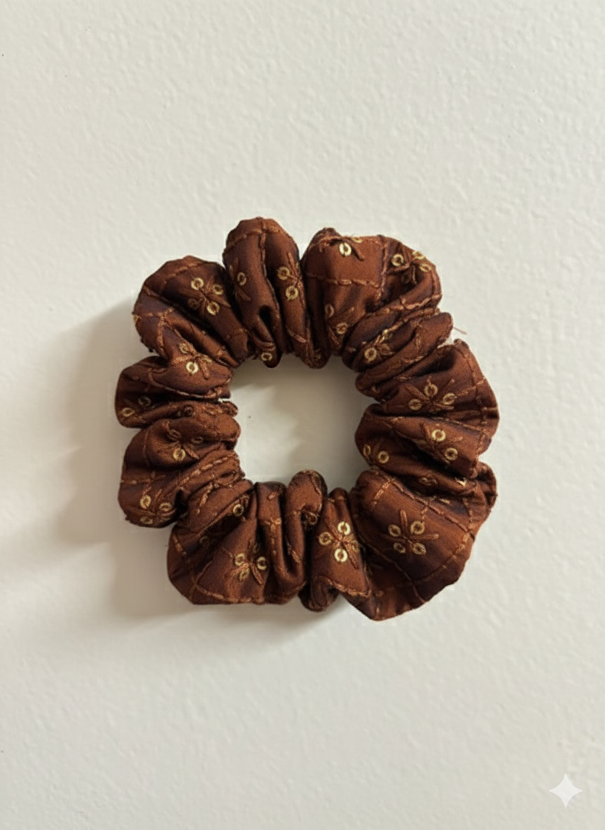 Brown scrunchie with gold accents on a white background